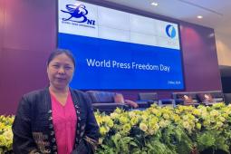 Photo of Nan Paw Gay standing in front of a large screen that says "World Press Freedom Day - 3 May 2024"