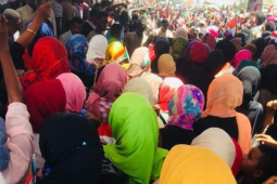 A group of Sudanese women gathered in protest with their backs to the camera