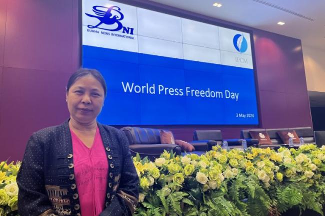 Photo of Nan Paw Gay standing in front of a large screen that says "World Press Freedom Day - 3 May 2024"