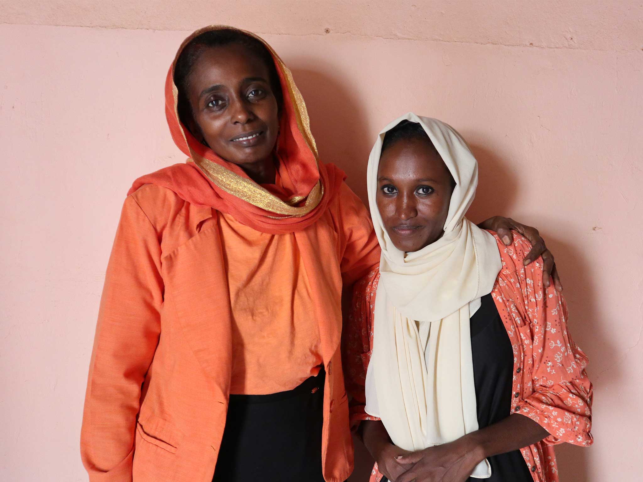 Two people stand side by side, one with an arm around the other, showing solidarity and shared social justice values.