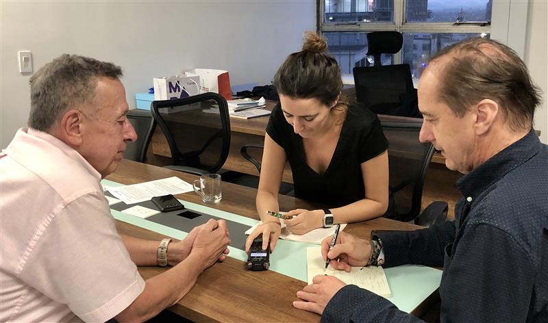 Three people sit around a table in discussion.