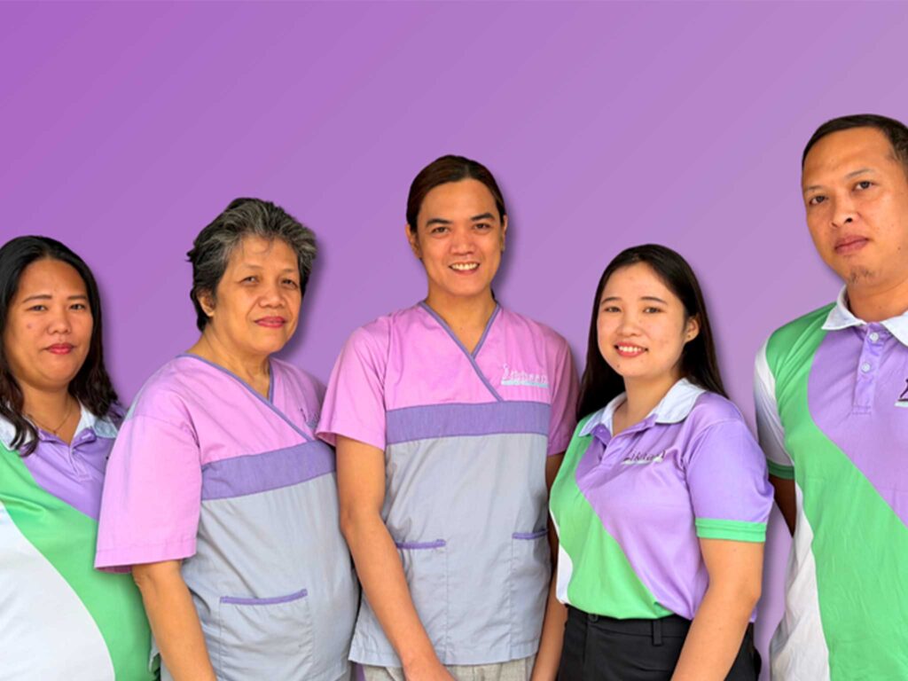 Five Likhaan health workers stand shoulder to shoulder wearing purple and green shirts.